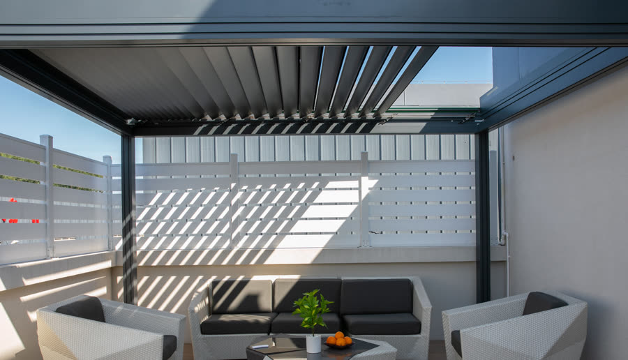 Aluminum louvers open, throwing bands of light across the patio